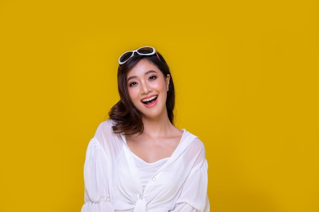 Retrato de Asia hermosa mujer joven feliz sonriendo alegre y mirando a cámara aislada sobre fondo amarillo de estudio