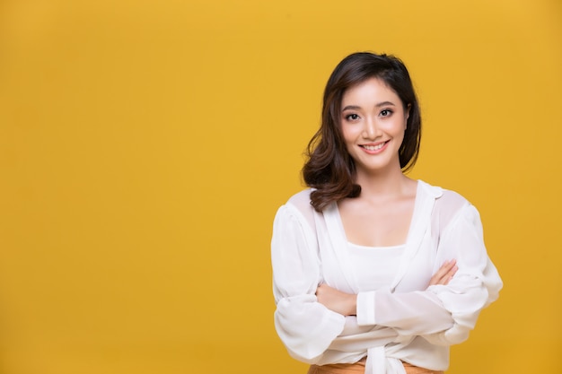 Retrato asiática hermosa mujer joven feliz sonriendo alegre y mirando a cámara aislada sobre fondo amarillo studio