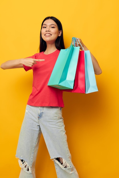 Retrato asiático hermosa mujer joven bolsas de compras en camiseta roja fondo aislado inalterado