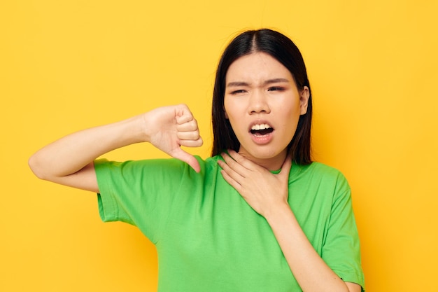 Retrato asiático hermosa mujer joven en camisetas verdes gestos con sus manos emociones fondo amarillo inalterado