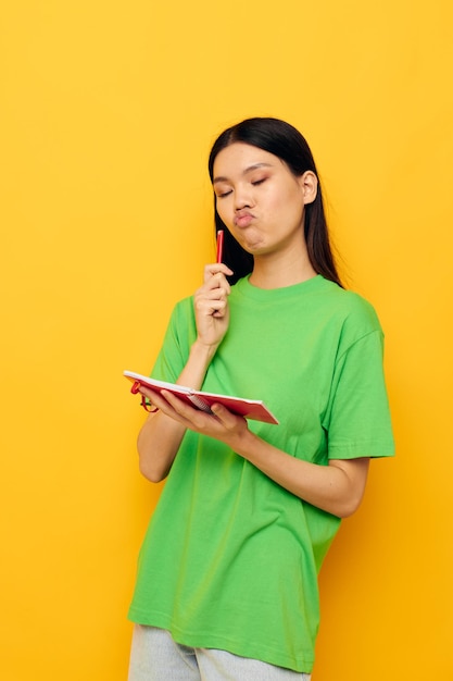 Retrato asiático hermosa mujer joven cuaderno y pluma aprendizaje educación fondo amarillo inalterado