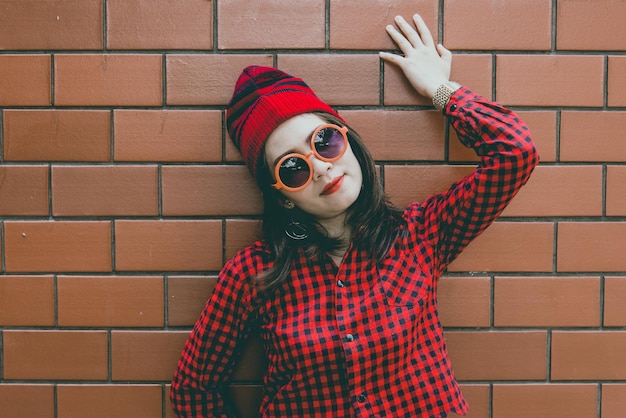 Retrato asiático hipster chica sobre fondo de pared de ladrillo usa sombrero rojo estilo vintage concepto de moda gente de tailandia