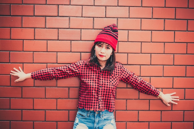 Retrato asiático hipster chica sobre fondo de pared de ladrillo usa sombrero rojo estilo vintage concepto de moda gente de tailandia