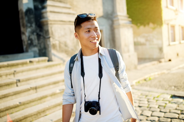 Retrato asiático joven del mochilero que viaja en la ciudad.