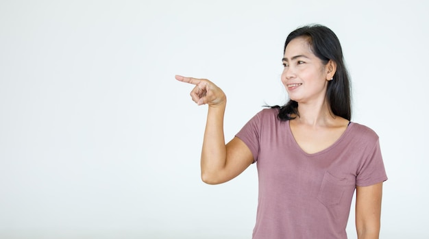 Retrato asiático mulher bonita vestindo camisa casual em pé poses, apontando o anúncio no fundo branco, cópia espaço em branco com um isolado olhar sorridente para a câmera.