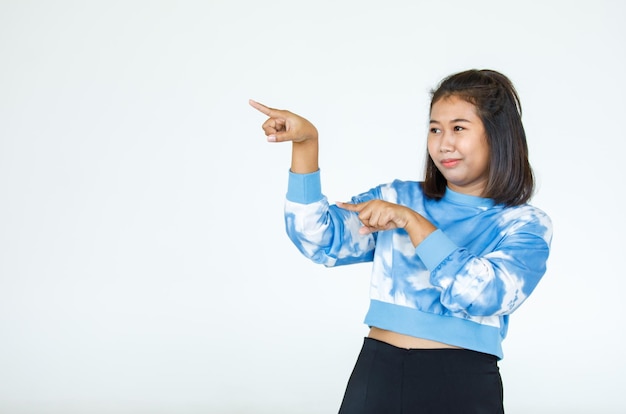 Retrato asiático mulher bonita vestindo camisa casual em pé poses, apontando o anúncio no fundo branco, cópia espaço em branco com um isolado olhar sorridente para a câmera.