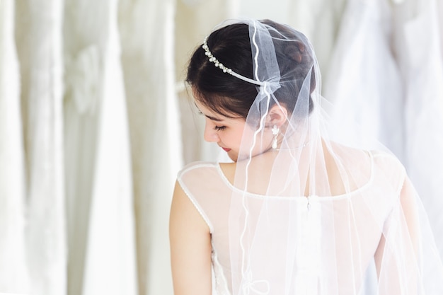 Retrato asiático de la señora linda que sonríe vestido de boda que lleva feliz