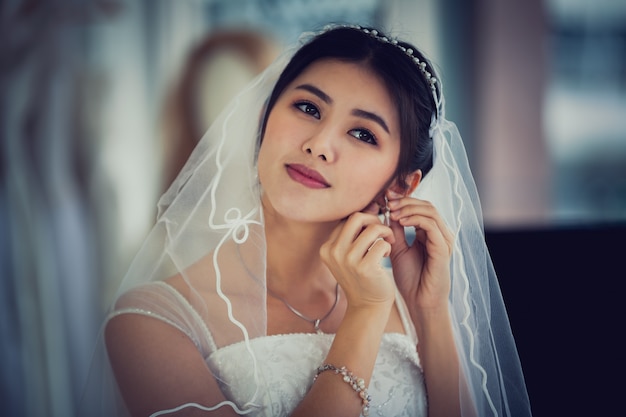 Retrato asiático de la señora linda que sonríe vestido de boda que lleva feliz