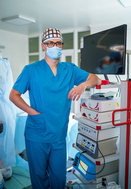 Retrato de asistente médico profesional en mascarilla quirúrgica cerca de equipos médicos. Quirófano del hospital moderno.