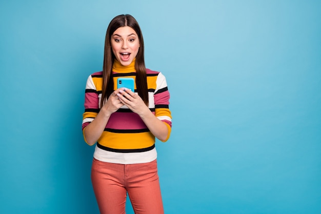 Retrato de asombrada chica cobarde usa teléfono inteligente recibe notificación de redes sociales impresionado grito wow Dios mío usa elegante traje rojo de otoño aislado sobre una pared de color azul