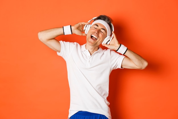 Foto retrato del atleta masculino de mediana edad despreocupado, escuchando música en auriculares