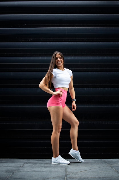 Retrato de atleta muscular atractiva deportista con pelo largo y piernas fuertes posando en el gimnasio.