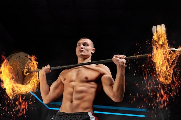 Retrato de un atleta que está levantando la barra en el gimnasio.