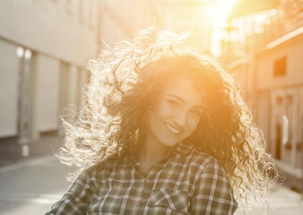 Foto retrato atmosférico de una joven y hermosa dama sonriente en la calle bajo la luz del sol de la tarde