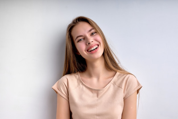 Retrato de atractiva adolescente caucásica aislada sobre fondo blanco sonriendo felizmente en casual ...