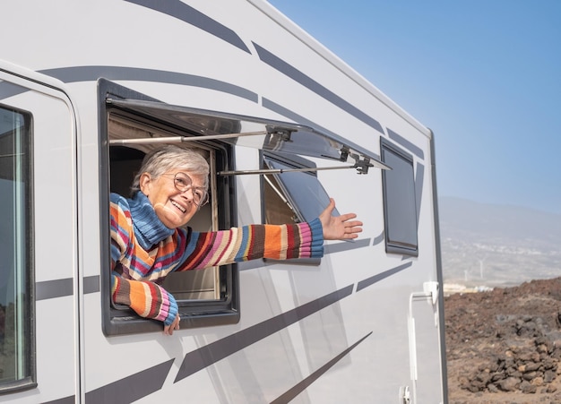 Retrato de una atractiva anciana feliz que viaja en autocaravana mirando por la ventana