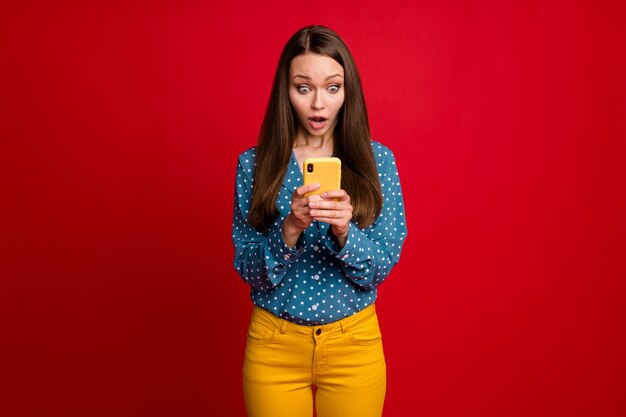 Retrato de una atractiva chica preocupada centrada utilizando el servicio web de gadget noticias falsas retroalimentación aislado de fondo de color rojo brillante