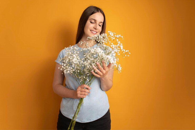 Retrato de atractiva chica soñadora de mente alegre sosteniendo flores gypsophila fondo de color amarillo