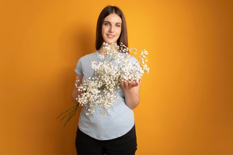 Retrato de atractiva chica soñadora de mente alegre sosteniendo flores gypsophila fondo de color amarillo