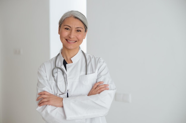 Retrato de una atractiva doctora madura con bata blanca y estetoscopio