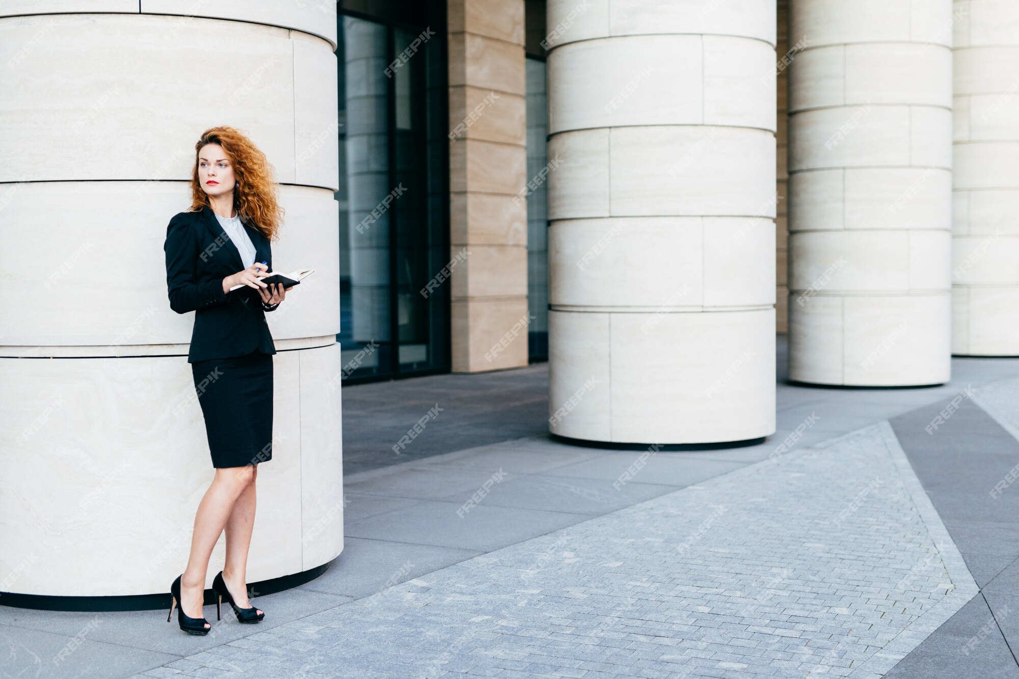Retrato atractiva empresaria vestida con ropa formal y zapatos con altos, sosteniendo el libro de bolsillo | Foto Premium