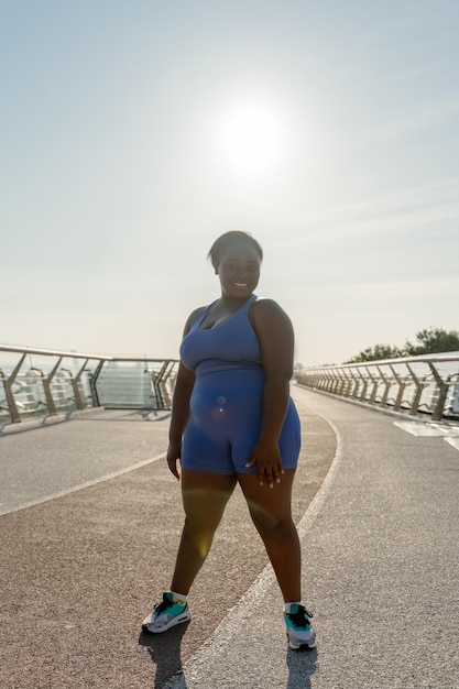 Retrato de una atractiva y hermosa mujer nigeriana vestida con ropa deportiva haciendo ejercicios en la calle