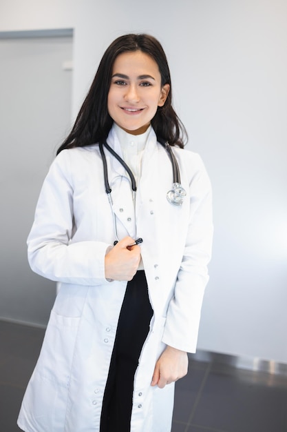 Retrato de una atractiva joven doctora con bata médica blanca