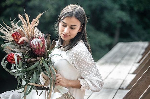 Retrato de una atractiva joven con un ramo de flores exóticas, un ramo de flores protea.