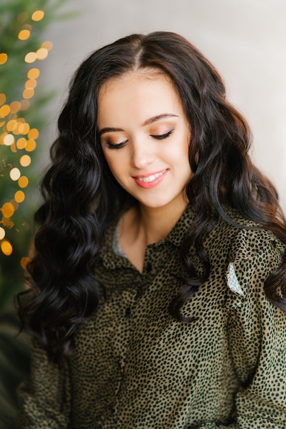 Retrato de una atractiva morena sonriente con maquillaje profesional con los ojos cerrados