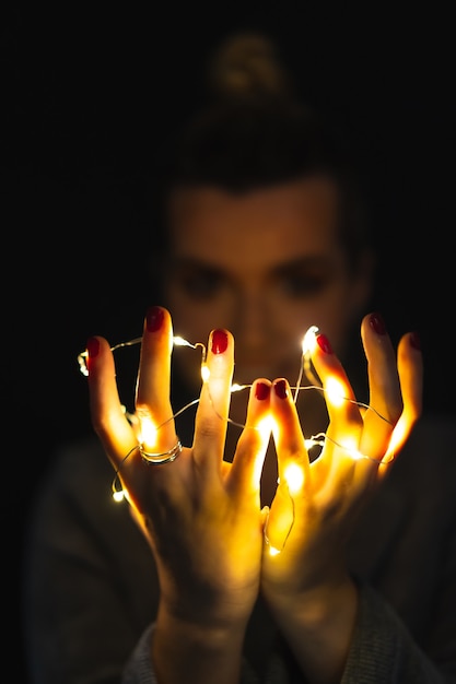 Foto retrato de una atractiva mujer caucásica con luces de cadena envueltas alrededor de sus manos