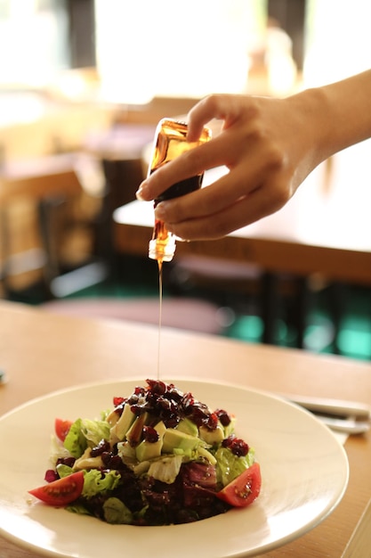 Retrato de una atractiva mujer caucásica sonriente comiendo ensalada centrada en la mano y el tenedor