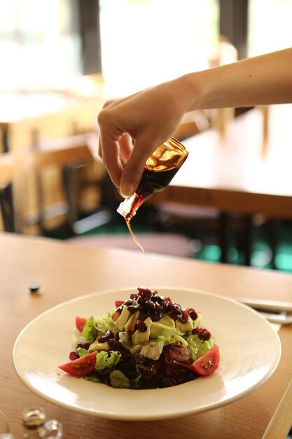 Retrato de una atractiva mujer caucásica sonriente comiendo ensalada centrada en la mano y el tenedor