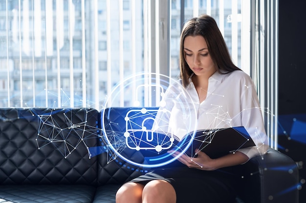 Retrato de una atractiva mujer de negocios que trabaja con documentos y piensa cómo proteger a los clientes información confidencial y seguridad cibernética Iconos de candado de holograma de TI sobre el fondo de la oficina