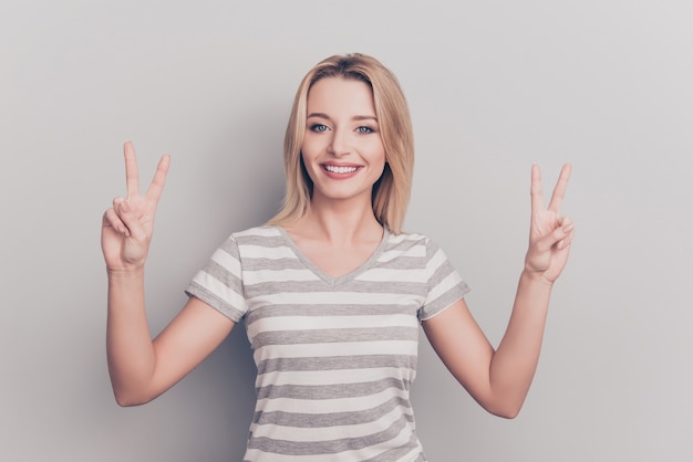 Retrato de atractiva mujer rubia haciendo el signo de la paz