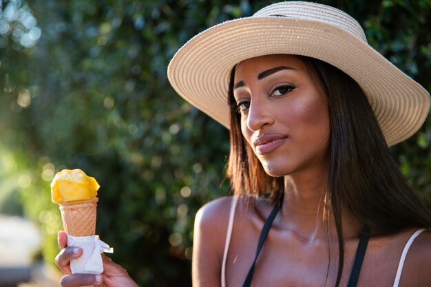 Retrato de una atractiva niña africana comiendo un helado en verano