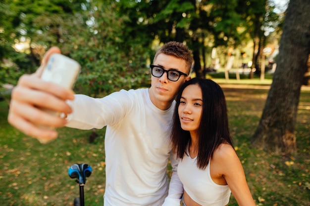 Foto retrato de una atractiva pareja fotogénica tomando selfies en el teléfono móvil