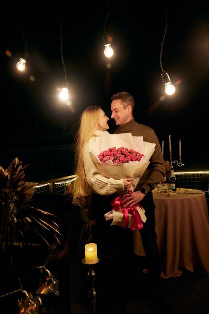 Foto retrato de una atractiva pareja sosteniendo un ramo de rosas