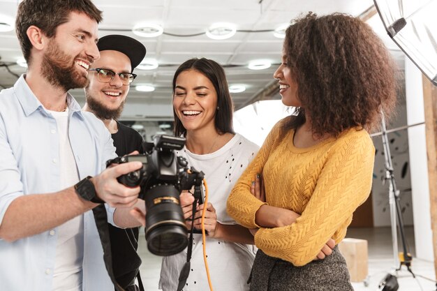 Foto retrato de atractivas personas multiétnicas hombres y mujeres mirando a cámara profesional durante la sesión de fotos de moda en estudio