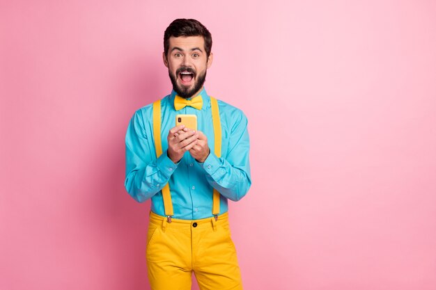 Retrato de atractivo chico barbudo sosteniendo celular cara emocionada