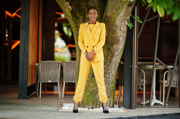 Retrato de atractivo contenido encantador de moda atractivo alegre alegre chica afroamericana usar chaqueta o traje de color amarillo vibrante brillante vivo.