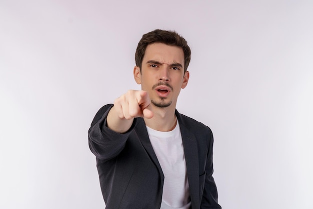 Foto retrato de un atractivo joven alegre señalando con el dedo a la cámara y de pie aislado sobre el fondo