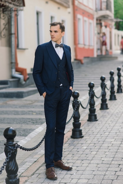 Retrato de un atractivo joven empresario de fondo urbano con traje y corbata.