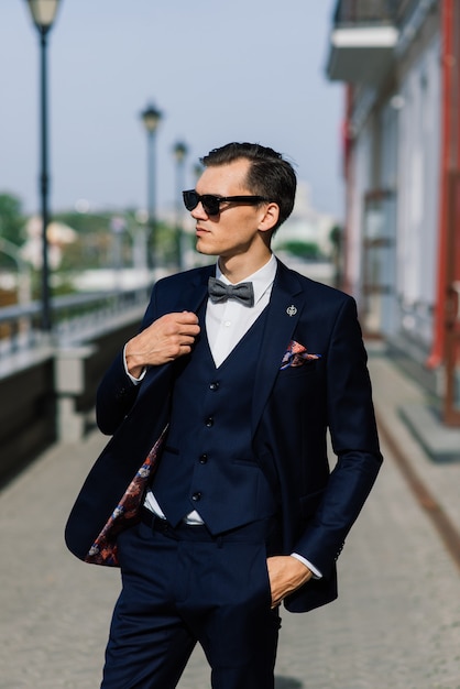 Retrato de un atractivo joven empresario de fondo urbano con traje y corbata.