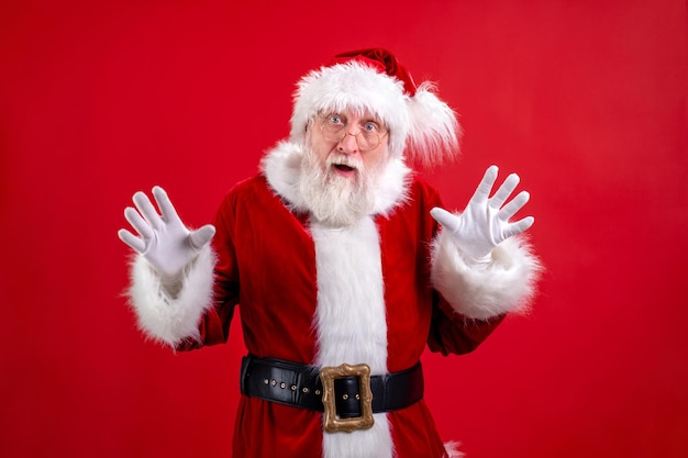 Retrato auténtico auténtico sorprendido sorprendido santa claus santa aislado sobre fondo rojo de estudio