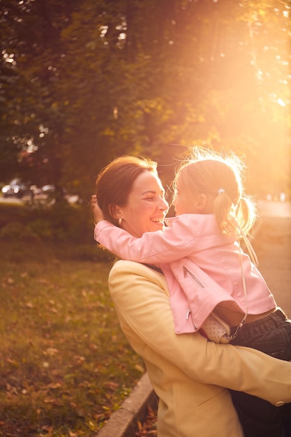 Retrato autêntico de mãe e filha no parque de outono durante o pôr do sol Aproveitando o tempo juntos