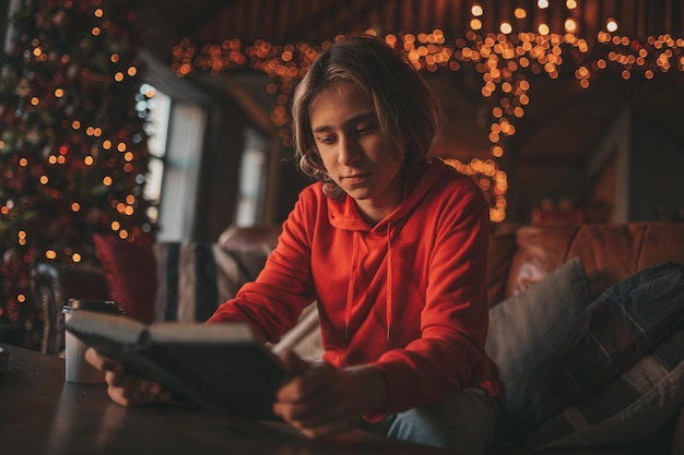 Retrato de un auténtico niño sonriente sincero leyendo un libro sobre la distancia estudiando en casa Navidad