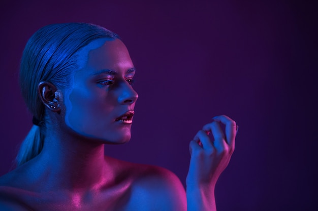 Foto retrato azul púrpura de modelo sexy desnuda en luz de neón sobre fondo oscuro