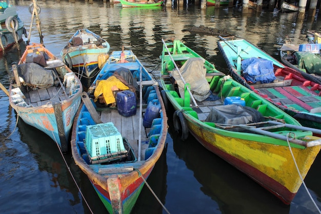 Retrato de barcos de pesca tradicionales que se apoyan en el muelle al lado del puerto de contenedores más grande de Indonesia