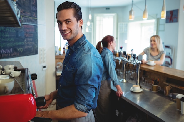 Foto retrato de barista mientras colega hablando con el cliente en el café