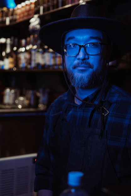 Retrato de un barman barbudo con sombrero en un bar.